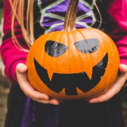 A girl holding a jack-o-lantern.