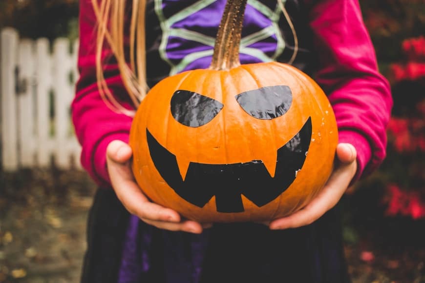 A girl holding a jack-o-lantern.