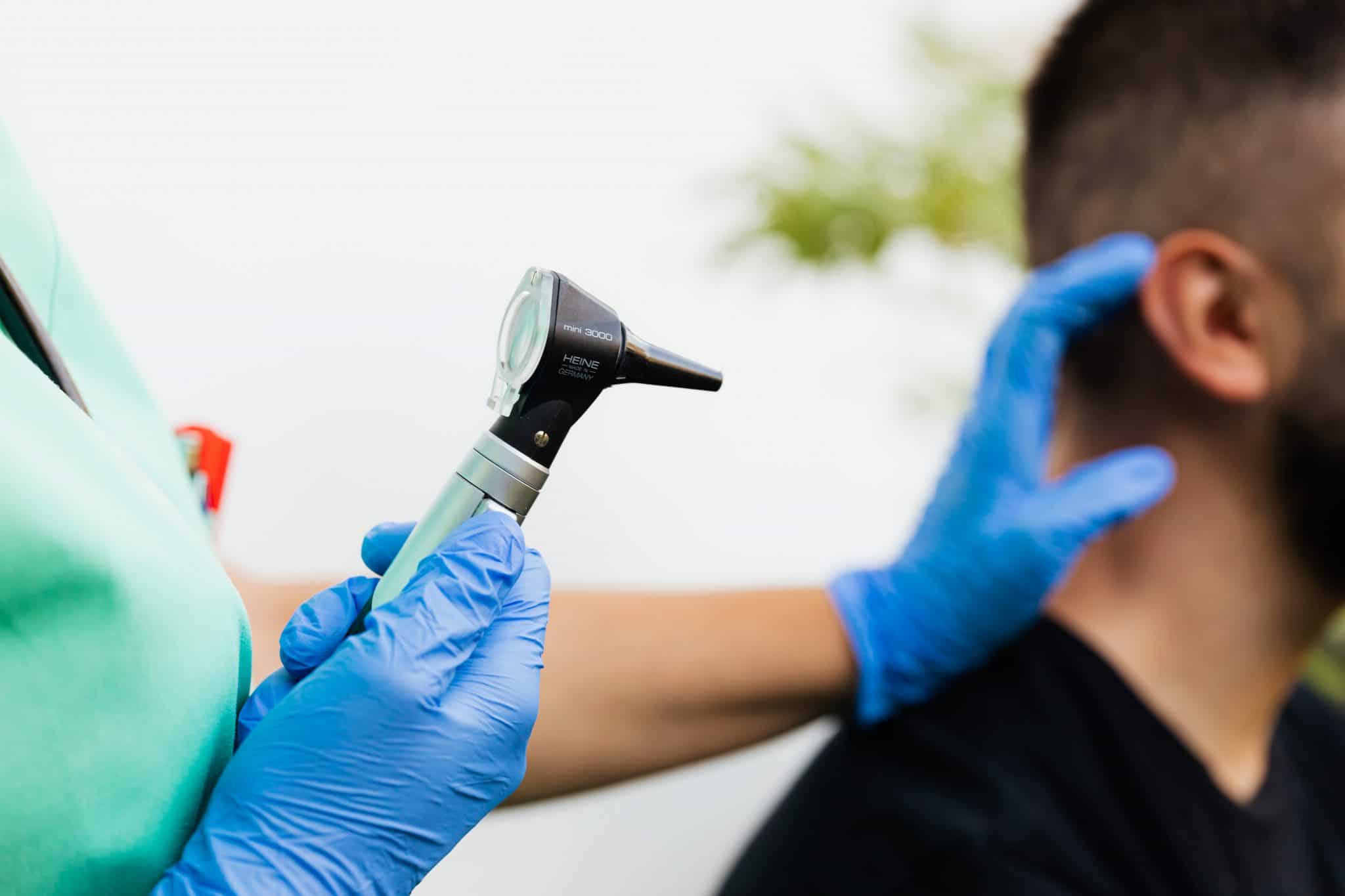 Doctor examining area behind man's ear.