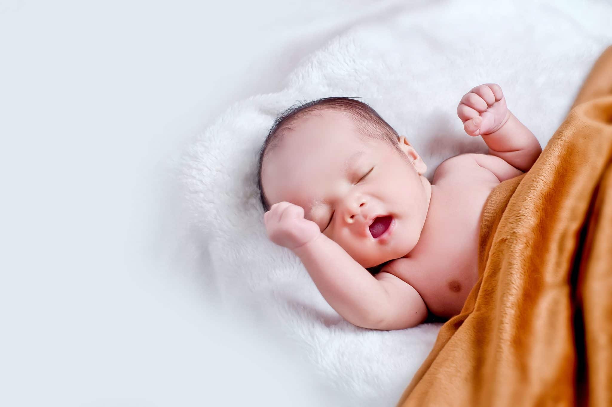 A newborn baby partially wrapped in a blanket.