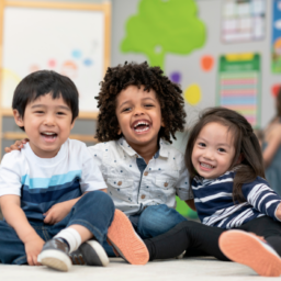 three preschoolers sit together in their brightly colored classroom