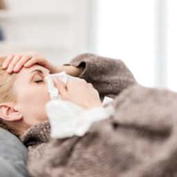 Woman sick in bed with a sinus infection.
