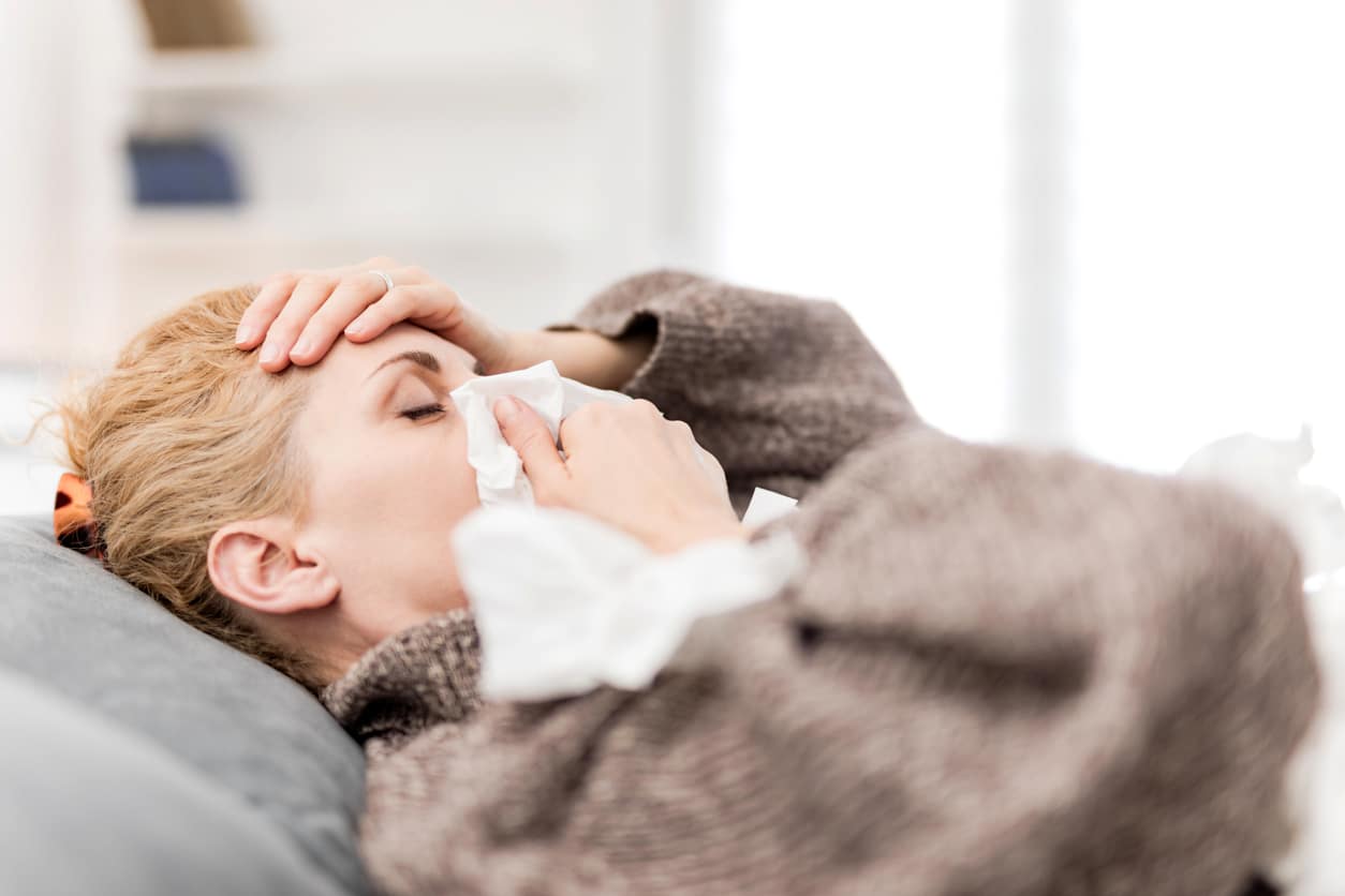 Woman sick in bed with a sinus infection.