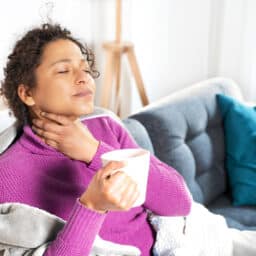 Woman holding her sore throat