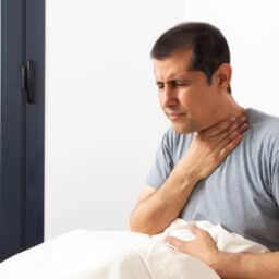Man touching his neck after waking up with a sore throat.