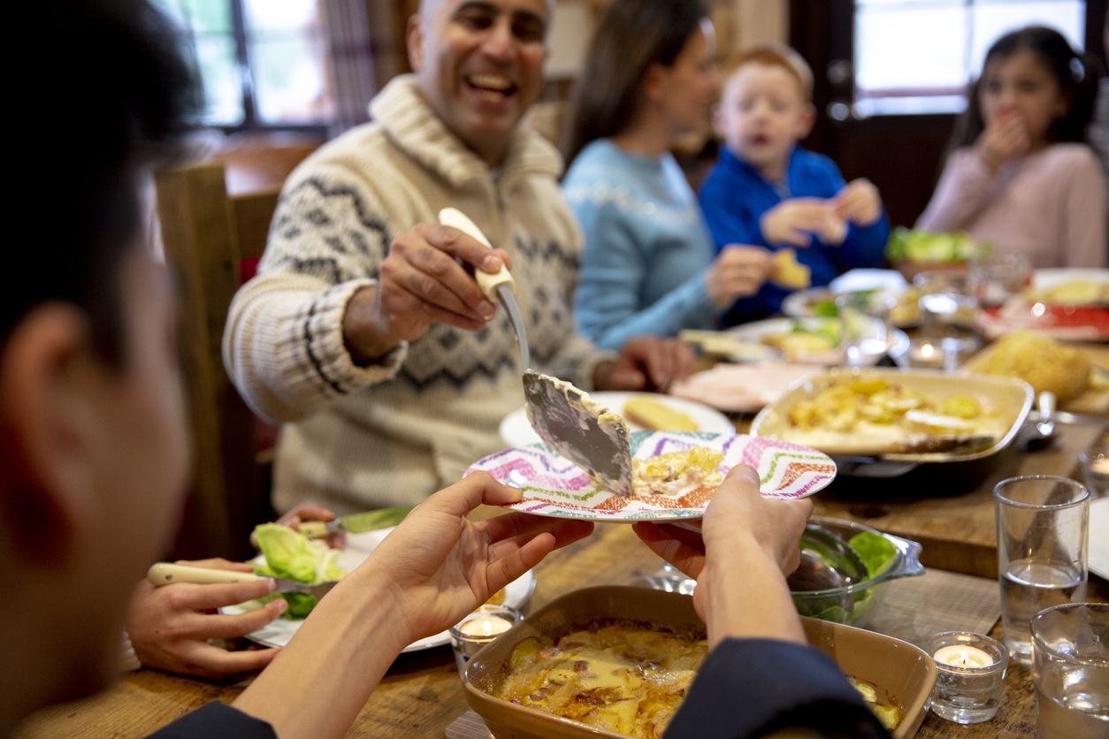 Family at the holiday dinner table serving up potatoes