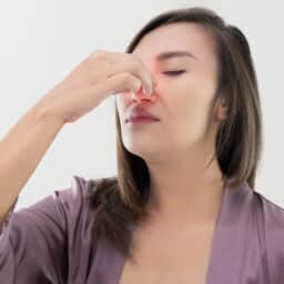 Woman holds nose in pain
