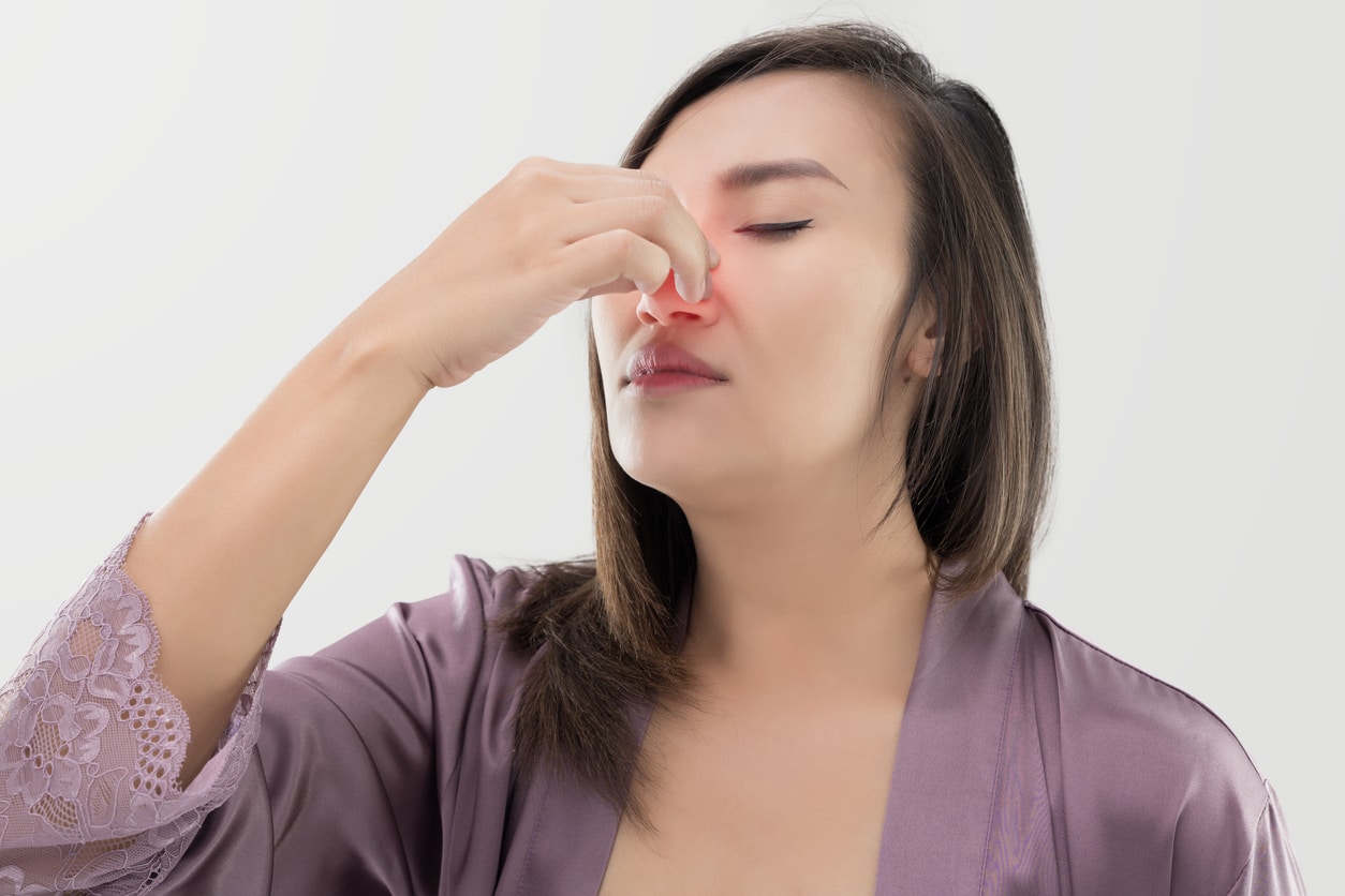 Woman holds nose in pain