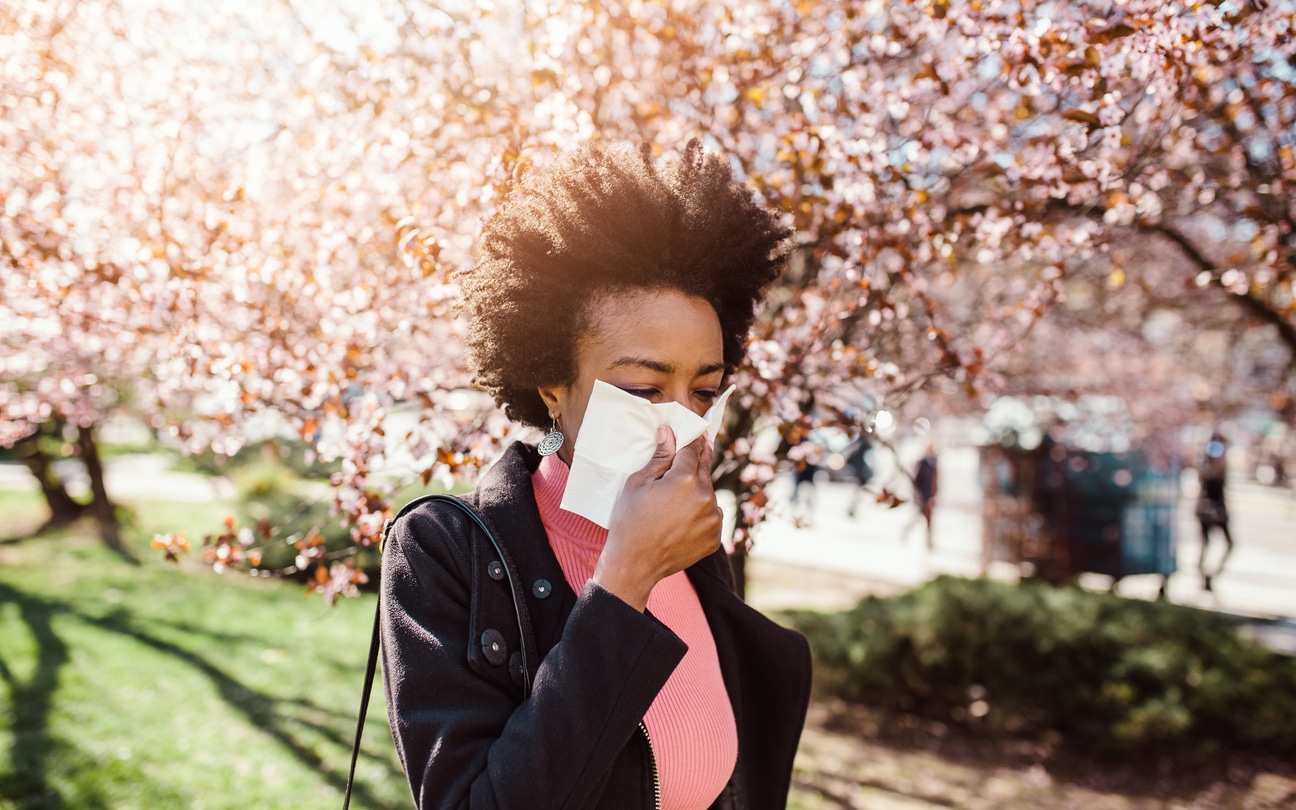 Woman sneezes near trees