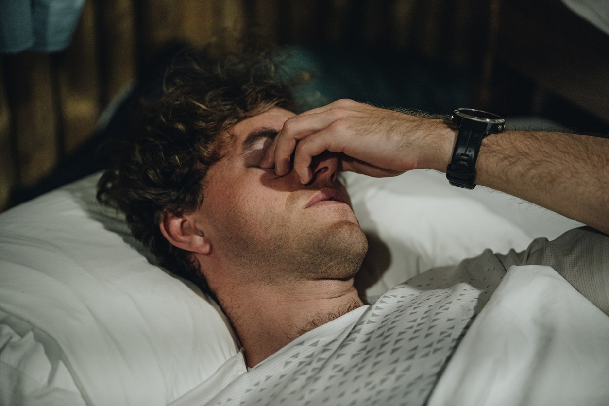 Man rubbing his eyes trying to sleep