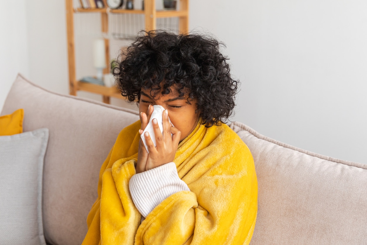 Young woman blowing her nose at home