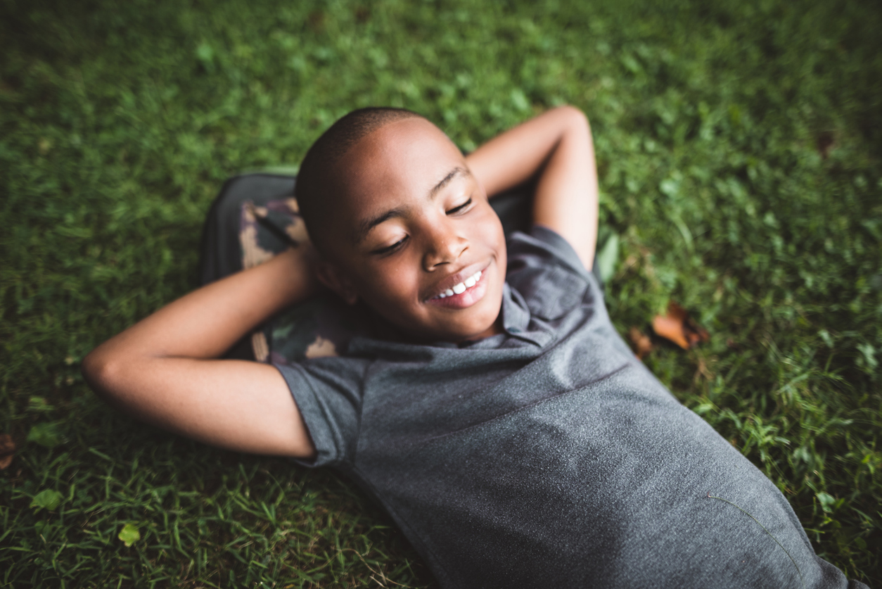 Young boy lays in grass