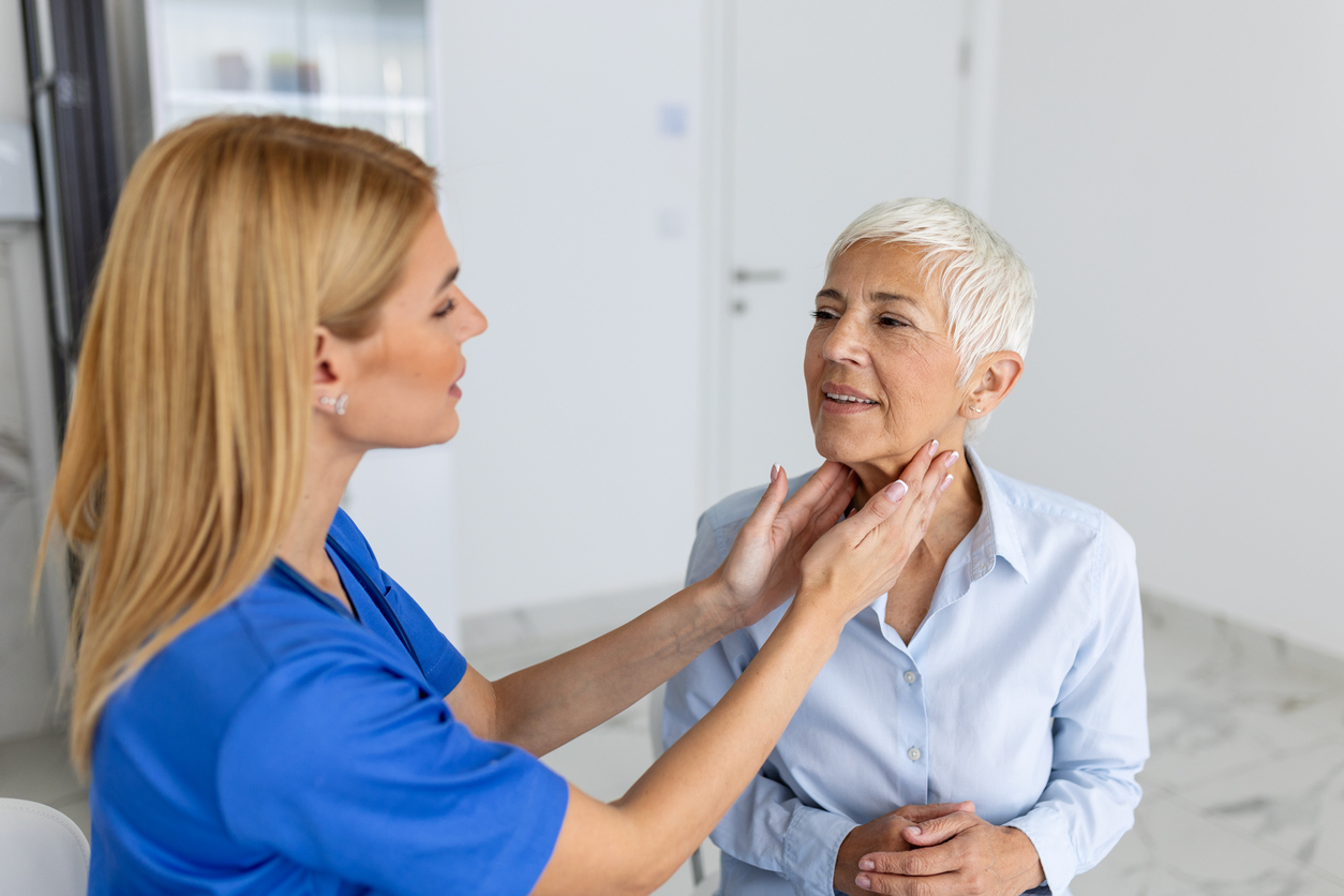 A woman has her jaw examined by a doctor.