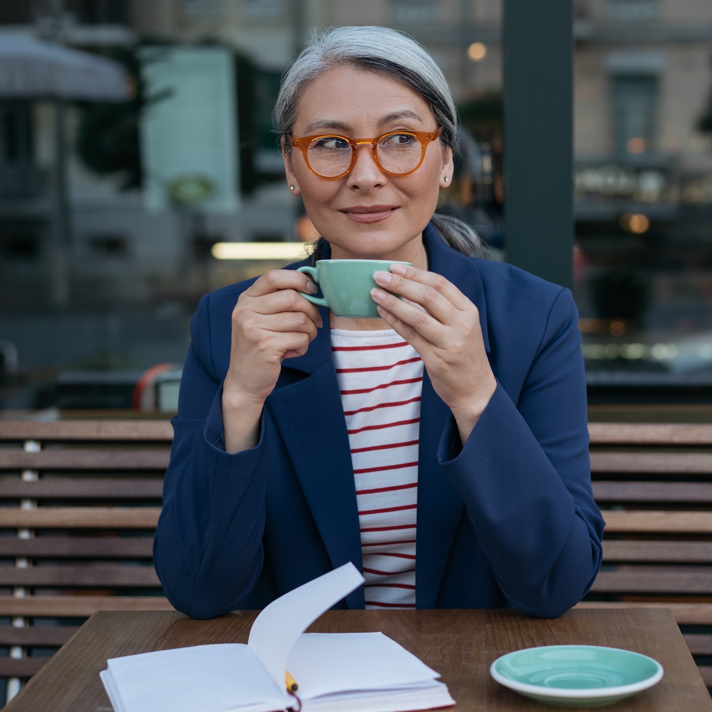 Woman drinking tea at a cafe and writing in her journal