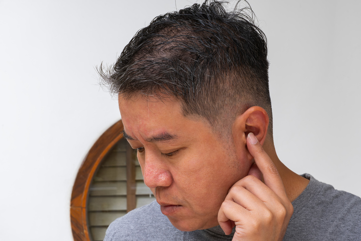 Man inspecting ear canal—possible sign of ear infection, hearing loss, or neural discomfort.